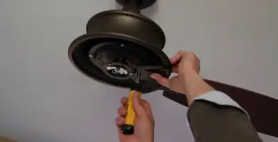 Electrician installing ceiling fan mounting bracket and fixture in Cleveland, OH