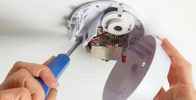Certified technician wiring smoke detector during installation in Cleveland, OH